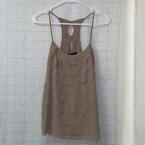 Tan tank with scalloped edges with a frayed texture. Cutout button back.